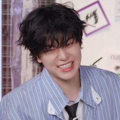 a young man with black hair wearing a blue shirt and tie smiling at the camera