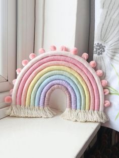 a rainbow shaped pillow sitting on top of a window sill