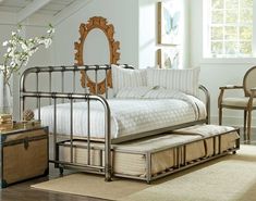 a bedroom with a metal bed frame and white sheets, beige rugs and wooden furniture