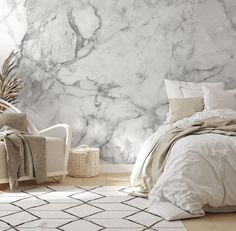 a bedroom with marble wallpaper and white bedding in the foreground, an area rug on the floor