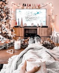 a living room decorated for christmas with lights on the tree and a flat screen tv