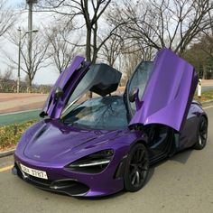 a purple sports car parked on the side of the road with its doors open and it's hood up