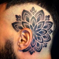 a man with a tattoo on his head has an ear piercing in the shape of a flower