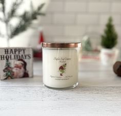 a white candle sitting on top of a table next to a christmas card and tree