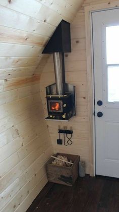 a small room with a wood stove in the corner and a box on the floor next to it