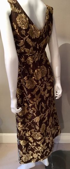 1970s Gold Floral Maxi Dress Perfect dress for the approaching festive season. Sleeveless empire line column maxi dress. Brown/ bronze wool synthetic mix fabric with gold lurex tinsel florals woven into the fabric. Sweetheart plunge neck line with a small bow. Straight skirt falls to ankle length. Fully lined. Zips up at the back. Size roughly 10 measures across shoulders-17in pit-pit-21in across empire line-17in across hips-21in length shoulder-hem-51in Gold Sleeveless Evening Dress For Festive Occasions, Gold Sequin Maxi Dress For Cocktail, Gold Fitted Evening Dress For Festive Occasions, Festive Gold Fitted Evening Dress, Glamorous Maxi Dress For Festive Party Season, Festive Formal Brown Dress, Vintage Gold Floor-length Dress, Gold Fitted Maxi Dress For Festive Occasions, Festive Gold Fitted Maxi Dress