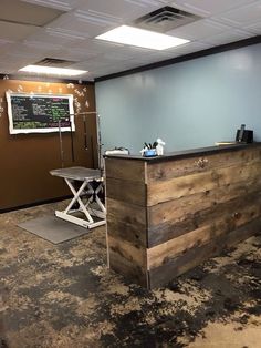 an empty office with a chalkboard on the wall and a wooden reception desk in front of it