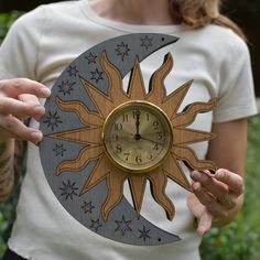 a woman holding a wooden clock with the sun and moon on it's face