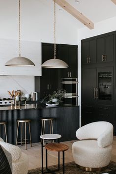 a black and white kitchen with stools, chairs and an island in the middle