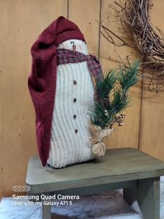 a stuffed snowman sitting on top of a wooden bench