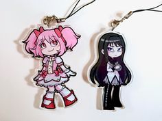 two keychains with cartoon characters on them hanging from strings, one is pink and the other is black