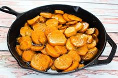 a skillet filled with cooked carrots on top of a wooden table