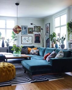 a living room filled with lots of furniture and plants on the wall above it's windows