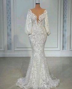 the back of a wedding dress on display in front of a white wall and floor