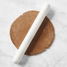 a white rolling pin sitting on top of a piece of paper next to a wooden slice