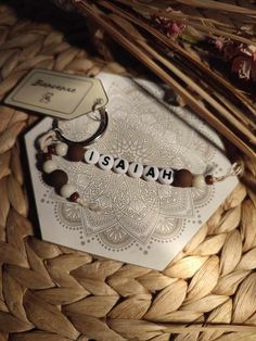 a bracelet with the word hawaii on it sitting on top of a wooden table next to some flowers