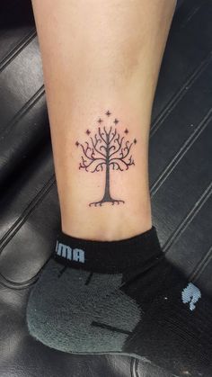 a small tattoo on the ankle of a woman's foot, depicting a tree with stars