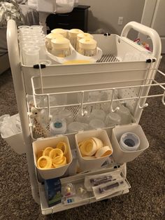 an open dish rack filled with dishes on top of a carpeted floor next to a bed