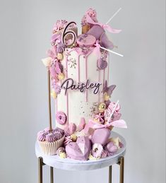 a pink and white cake on a table with cupcakes