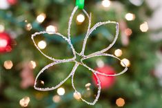 an ornament shaped like a flower hanging from a string on a christmas tree