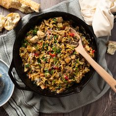 a skillet filled with rice and vegetables on top of a blue plate next to bread