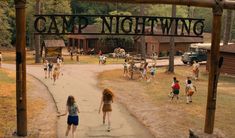 two girls walking down a path under a sign that says camp nightwing