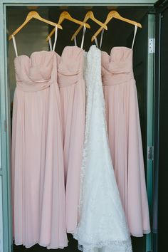 three bridesmaid dresses hanging in a closet