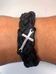 a close up of a person's arm wearing a bracelet with a cross on it