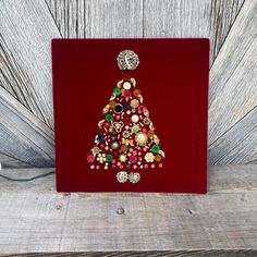 a red box with a christmas tree made out of buttons and other things on it