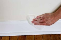 a person with their hand on the edge of a white strip of paper near a wall