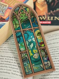 a stained glass window sitting on top of an open book next to a pile of books