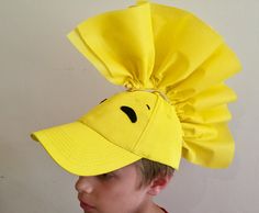 a young boy wearing a yellow hat with a smiley face drawn on it's side