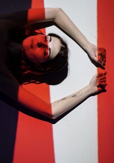 a woman with her arms spread out in front of an orange and white striped wall