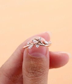 a woman's hand holding a gold ring with three leaves on it and two diamonds in the middle