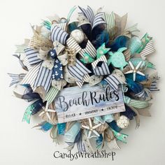 the beach rules wreath is made with blue, white and green ribbon bows on it