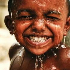 a little boy that is standing in the water with his face covered in brown paint