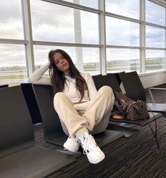 a woman sitting in an airport waiting for her luggage to be taken off the plane