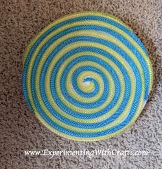 a blue and green rug on the floor with a circular design in the center that looks like a spiral