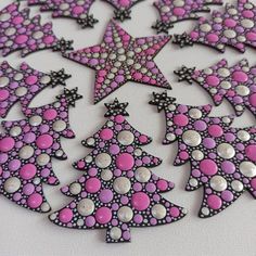 some pink and black christmas trees on a white table top with silver dots in the middle