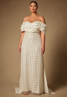 a woman wearing a white dress with an off the shoulder top and long flowing skirt