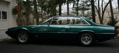 a green car parked in front of a garage