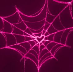 a spider web on a dark background with pink light in the center and white lines across it