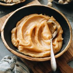 a wooden bowl filled with peanut butter and nuts