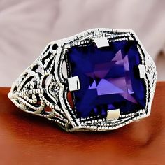 Elevate your jewelry collection with this stunning Vintage 3.00 Carat Princess Cut Vivid Purple Lab-Created Amethyst Solitaire Filigree Ring, a true masterpiece crafted for those who appreciate timeless elegance and unique design. Made from 925 Solid Sterling Silver, this exquisite ring is not only beautiful but also durable, ensuring it remains a cherished piece for years to come. The ring is stamped "925," guaranteeing its authenticity and quality. The vivid purple hue of the lab-created amethyst captures the eye, making it a statement piece perfect for any occasion, whether it's a formal event or a casual outing with friends. This ring stands out with its intricate filigree detailing, showcasing a blend of traditional craftsmanship and modern design aesthetics. The princess cut of the a Classic Amethyst Birthstone Ring Gift, Classic Purple Ring As Gift, Classic Purple Rings As Gift, Silver Art Deco Amethyst Ring For Formal Occasions, Art Deco Hallmarked Amethyst Ring For Anniversary, Heirloom Style White Gold Amethyst Ring Gift, Heirloom Amethyst Ring In White Gold For Gift, Heirloom Style Amethyst Ring In White Gold, Heirloom White Gold Amethyst Ring As Gift