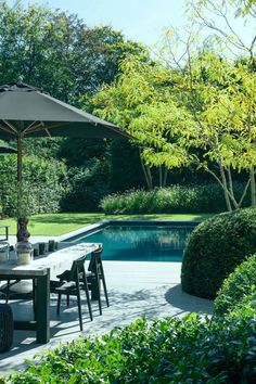 an outdoor dining area with table, chairs and umbrella next to a large swimming pool