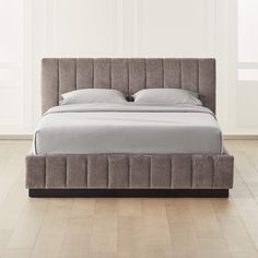 a bed that is made up with grey linens and white sheets on top of it