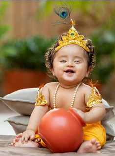 a baby girl wearing a tiara and holding a red ball