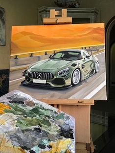 a painting of a green sports car is on an easel next to a bed