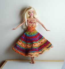 a barbie doll wearing a multicolored dress on top of a white countertop