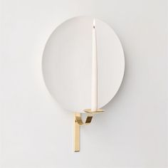 a white plate with a lit candle on it next to a wall mounted light fixture